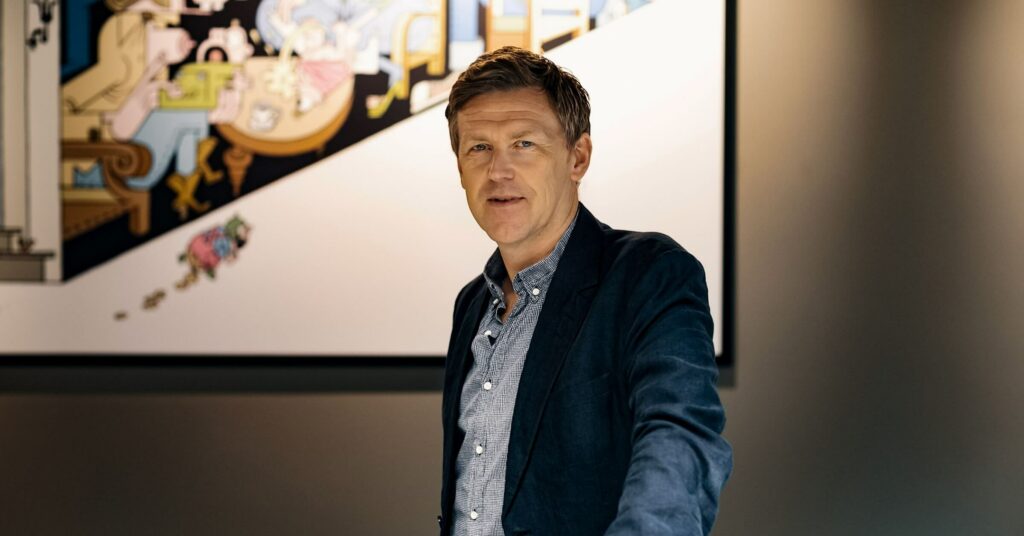 Jørgen W. Bjerke står med dressjakke foran moderne kunst.