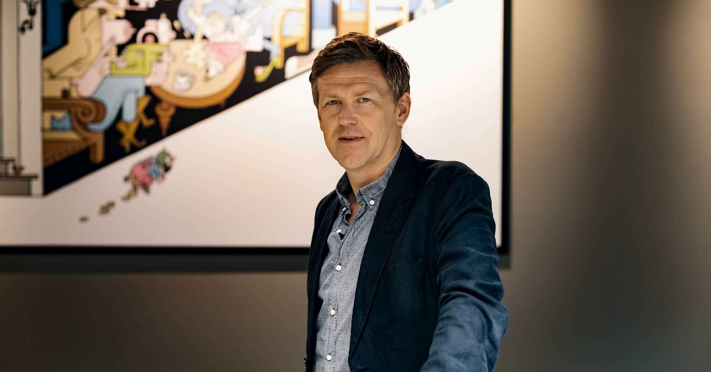 Jørgen W. Bjerke står med dressjakke foran moderne kunst.